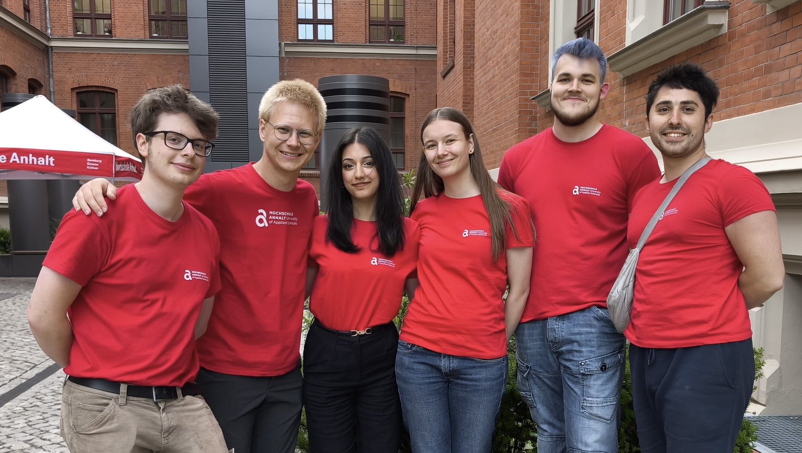 Sechs Mitglieder des FSR INS in roten Shirts vor dem Fachbereichsgebäude